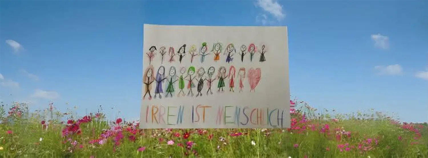 Eine Kinderzeichnung. Verschiedene Personen stehen in 2 Reihen. Darunter steht geschrieben Irren ist menschlich.